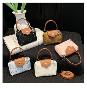 Mini denim crossbody bag detail featuring star print, brown leather flap and flower charm.