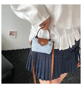 Mini denim crossbody bag detail view featuring light blue star pattern and brown leather trim.