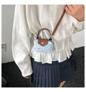 Detailed shot of the mini denim crossbody bag worn by the model, showing compact style.
