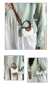 Detail view of a small white star-printed canvas handbag with brown leather handle and strap.
