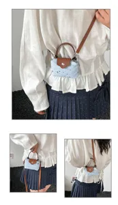 Detailed look at the stylish denim dumpling crossbody bag with star prints and brown leather trim.