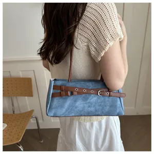 Close-up detail shot of the chic blue denim shoulder bag with a stylish brown belt.