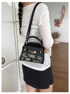 Black embroidered top handle handbag detail showing intricate floral details and gold hardware.