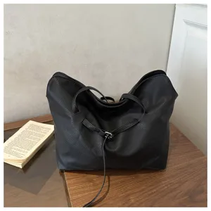 Elegant black leather tote bag for women, stylish minimalist shoulder bag with belt detail.