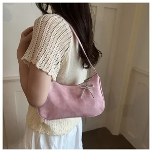 Detailed view of chic pink shoulder hobo bag featuring sparkling rhinestone bow pendant.