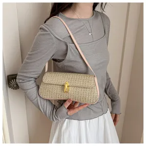 Detailed view of stylish straw woven baguette shoulder bag with pink leather trim and gold lock.