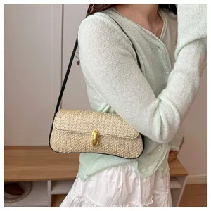 Straw underarm shoulder bag detail showing woven texture and elegant gold-tone metal lock clasp.
