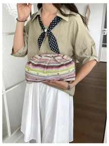 Λεπτομέρεια καλοκαιρινής πλεχτής τσάντας clutch με κομψές ρίγες και μεταλλικά τρουκς.