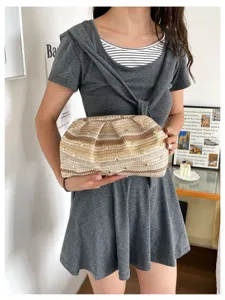Λεπτομερής όψη γυναικείας τσάντας clutch από ψάθα καλοκαιρινής με μεταλλικά τρουκς και πλισέ.