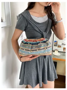 Λεπτομερής όψη γυναικείας τσάντας clutch από ψάθα με ρίγες και μεταλλικά τρουκς.