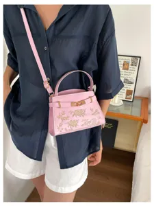 Detail shot of pink women handbag with gold hardware and floral embossing, stylish and elegant.