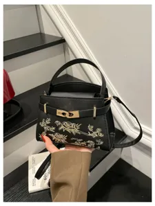 Elegant black leather handbag with exquisite gold embroidery and metal lock, perfect for daily use.