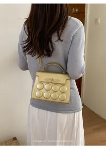 Stylish gold crossbody bag featuring unique bubble texture and elegant metal lock design.