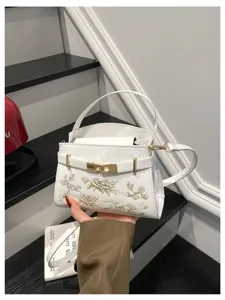 Chic white handbag with gold embroidery and metal lock, elegant shoulder bag for women.