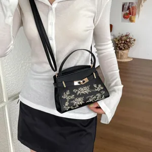 Elegant black women handbag with gold floral embroidery, top handle and crossbody strap design.