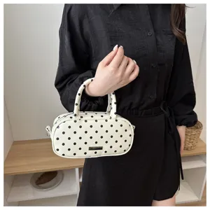 White black polka dot cylindrical cosmetic bag detail, portable handbag close-up shot.