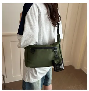 Detailed view of the green crossbody bag showing zipper pocket, adjustable strap, and pouch.