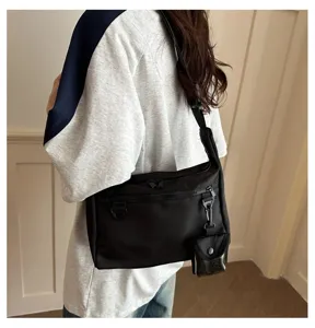 Casual black nylon crossbody shoulder bag with zipper pockets and small pouch accessory.
