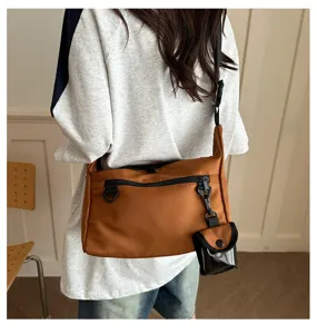 Detailed view of a stylish brown canvas cross-body shoulder bag with a small pouch.