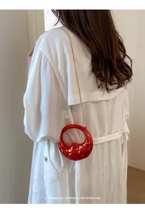 Mini red glossy circular cross-body bag with thin gold chain stylish minimalist fashion accessory