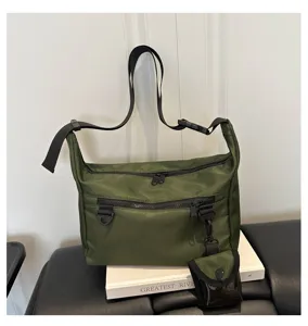 Detail view of the green nylon crossbody bag showcasing durable zippers, D-ring and utility strap.