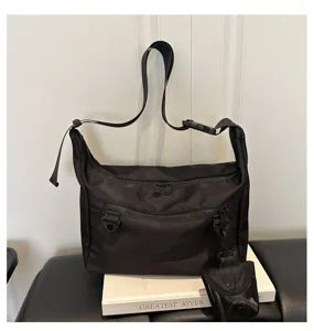 Detail of black nylon crossbody bag featuring front zipper pockets and convenient small pouch.