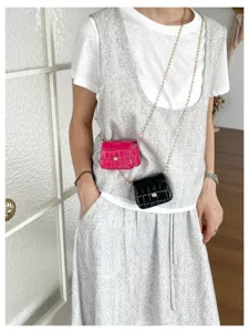 Detailaufnahme der trendigen Mini Kroko Muster Umhaengetaschen mit Kette als Accessoire.