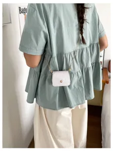 Detailansicht einer kleinen weißen Krokodilmuster Umhängetasche mit edler Goldkette.