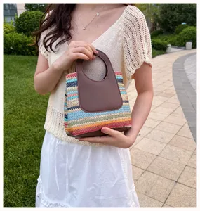 Summer woven straw handbag with brown leather handle, stylish beach tote bag detail.