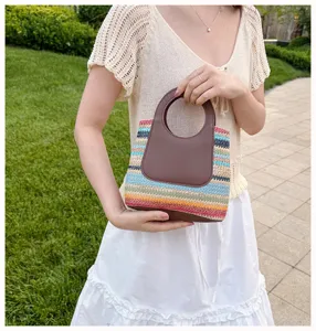 Detail view of a stylish summer straw woven handbag with colorful stripes and brown PU round handles.