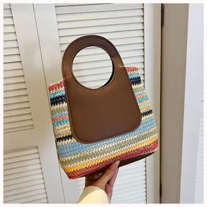 Detailed view of summer colorful woven straw handbag with brown round leather handle, beach style.