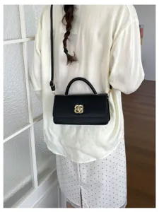 Elegante borsa a spalla in pelle nera da donna con chiusura dorata chic e manico superiore.