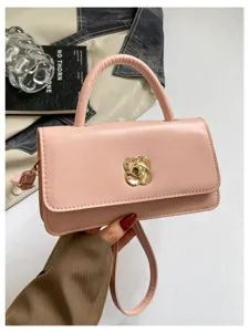 Vista di dettaglio di una chic borsa a spalla rosa con chiusura a torsione dorata e manico elegante.