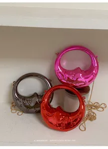 Detail shot of metallic crescent mini handbags in pink, red, and grey with chic chains.