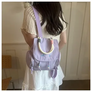 Detalle de una elegante mochila informal lila claro con asas de cuerda y abalorios.
