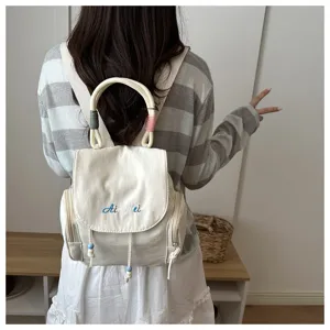 Vista detallada de la mochila de lona informal con asa y bordado para el uso diario.