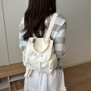 Mochila informal de lona para mujer, vista trasera con cuentas y solapa bordada elegante.