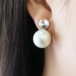 Dettaglio in primo piano di orecchini clip con zircone e grande perla dal design elegante.