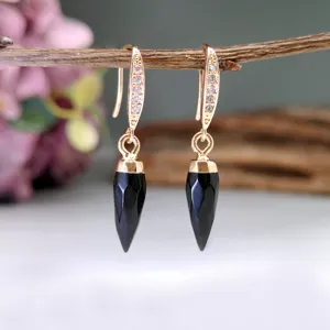 Eleganti orecchini pendenti dorati con pietre naturali nere sfaccettate e dettagli.