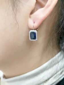 Dettaglio in primo piano di orecchini pendenti in zircone blu con ganci francesi sicuri.
