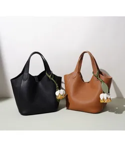Vue détaillée de sacs seau cabas en cuir véritable noir et brun avec des charms floraux.