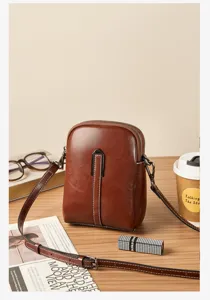 Detailed view of a vintage brown leather small crossbody bag with thin strap and metal buckle.