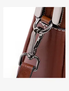 Close-up detail of brown leather women crossbody bag metal hardware strap clasp and zipper.