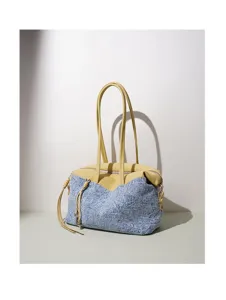 Détail de sac à épaule patchwork en denim et cuir montrant un design unique et soigné.