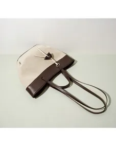 Canvas and brown leather tote bag detail view, highlighting contrast color and fine texture.