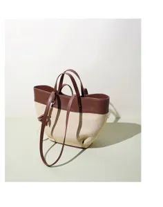 Detail view of color-block canvas and soft leather tote bag, featuring sturdy handles and spacious design.