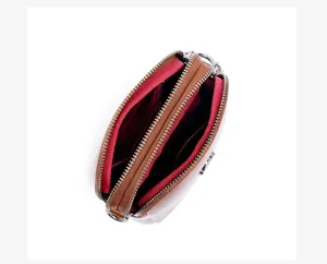 Detail view of the leather crossbody bag with dual zippers and red lining for daily use.