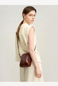 Detail view of stylish brown leather crossbody phone bag worn by female model showing elegance.