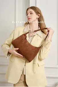 Detailed view of the brown suede shoulder bag with adjustable strap and metal hardware.