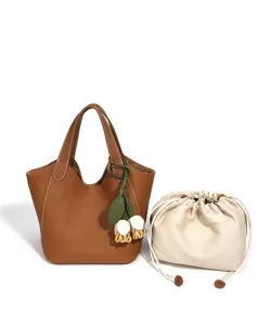 Gros plan détaillé du sac seau en cuir marron avec coutures contrastées et pendentif.